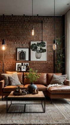 a living room with brick walls and leather couches, coffee table, pictures on the wall