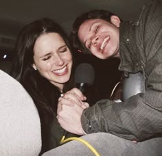 a man and woman sitting next to each other with a microphone in front of them