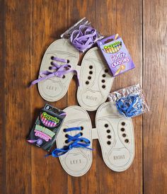 four pairs of shoes with purple and blue laces on them sitting on a wooden floor