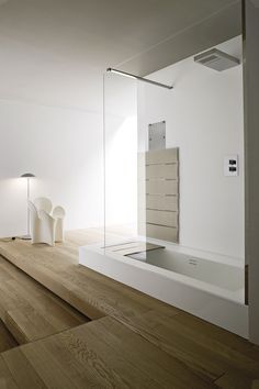 an empty room with wooden floors and white walls, including a bathtub in the center