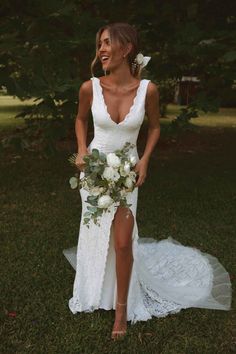 a woman in a white wedding dress holding a bouquet and posing for the camera with her legs slited