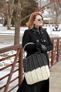 a woman is standing on a bridge carrying a crocheted handbag in the snow