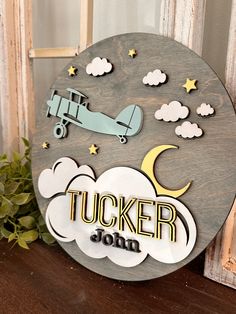 a wooden sign that says tucker jon with an airplane in the sky and clouds above it