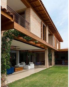 an outdoor living area with couches and tables on the grass next to a large brick building