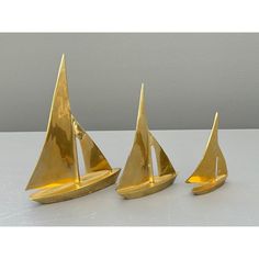 three brass sailboats are sitting on a table