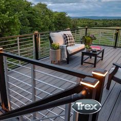 a deck with furniture and lights on it, overlooking the trees in the background at dusk