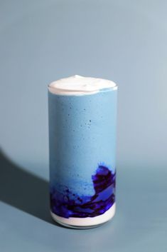 a blue and white vase with purple designs on the bottom is sitting on a gray surface