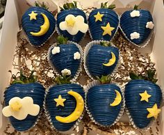 a box filled with blue and yellow cupcakes topped with stars and moon decorations