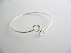 Offered for sale is a wonderful Tiffany and Co. Elsa Peretti Sterling Silver Double Open Heart Bracelet / Bangle.   The bangle is made from solid Tiffany silver with an Open Heart that accentuates each end.  Simple, classic and yet a very versatile piece that allows you to combine the bangle with almost any other piece of jewelry you already own.  Great piece to wear to work, or for just going to dinner with friends in jeans or a pretty dress.    The style is classic Tiffany, making it a pi Tiffany Bangle Tiffany & Co., Sterling Silver Bracelets Women Tiffany & Co., Tiffany And Co Bracelet, Heart Bangle Bracelet, Open Heart Necklace, Elsa Peretti, Dinner With Friends, Gift Love, Tiffany And Co