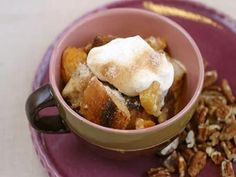 a bowl filled with fruit and nuts on top of a purple plate next to a spoon