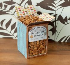 a box filled with granola sitting on top of a wooden table next to a wall