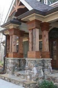 the front porch is made out of wood and has stone pillars on each side, along with