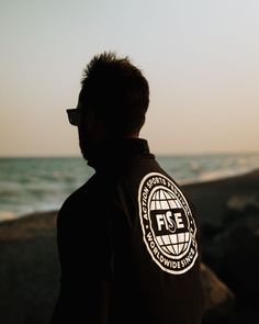 a man standing in front of the ocean with his back to the camera