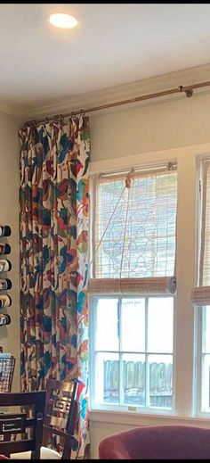 a living room filled with furniture and windows covered in colorful curtained drapes