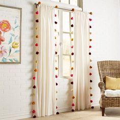 a chair sitting next to a window covered in pom - poms