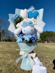 a bouquet of crocheted teddy bears is held by someone's hand