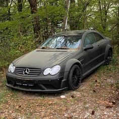 a mercedes benz coupe is parked in the woods