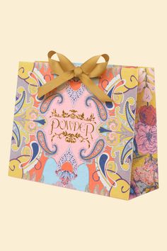 a small gift bag with a bow on the top and an ornate pattern in gold