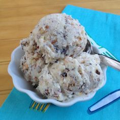 two scoops of ice cream in a white bowl on a blue napkin next to a fork