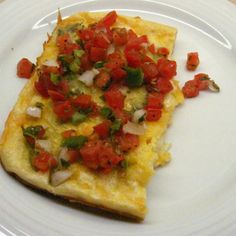 an omelet with tomatoes and onions is on a white plate, ready to be eaten