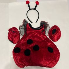 a red lady bug costume with black polka dots on it's chest and ears