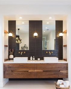 a bathroom with two sinks, mirrors and lights on the wall in front of it