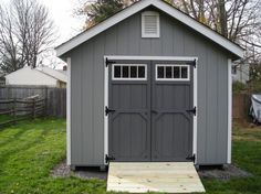 a gray shed sitting on top of a lush green field