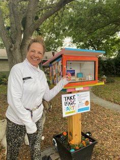 a woman standing next to a colorful mailbox with the words take leave art written on it