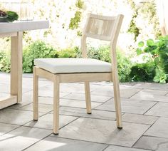 a wooden chair sitting on top of a stone floor next to a table and chairs