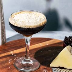 a close up of a wine glass on a table with cheese and other food items