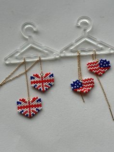 three pieces of beaded earrings hanging on a clothes hanger, with the flag of england painted on them