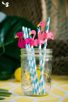 two pink flamingos and one blue striped straws in a mason jar