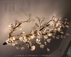 a branch with white flowers and lights hanging from it's centerpiece in a room