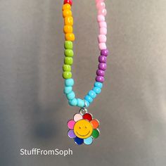 a multicolored beaded necklace with a smiley face charm hanging from it's end