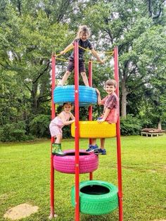 three children playing on a playground made out of tires