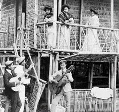 an old black and white photo of people playing music on the porch of a house