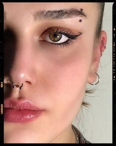 a woman with piercings on her nose and nose ring, looking at the camera