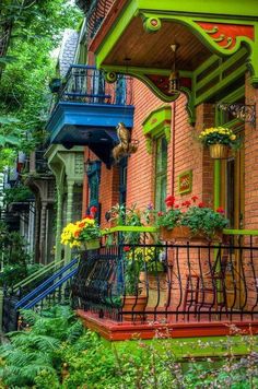 an old brick house with colorful balconies and flowers on the balcony, surrounded by greenery