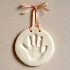 a white ceramic ornament with a hand print hanging from it's side