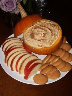 a white plate topped with lots of food on top of a wooden table next to an orange pumpkin