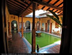 an indoor swimming pool surrounded by wooden pillars