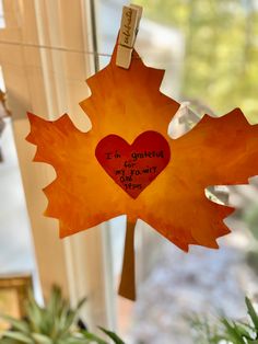 a maple leaf with a heart hanging from it's side on a window sill