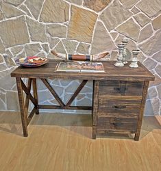 a wooden table sitting in front of a stone wall with vases and plates on it