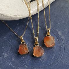 So simple and so cool with an earthy boho vibe! Absolutely gorgeous and and one-of-a-kind genuine carnelian crystals are set in a 14k gold plated bezel. The back of the setting is open to allow light to shine through these beautiful stones. . Each pendant is made from genuine carnelian and set by hand so no two are exactly alike. Soulful, earthy, and oh so cool.Carnelian is a birthstone for August and the zodiac sign Virgo.*Choose your chain- Options for 16" satellite chain with extender, 16" bo Earthy Agate Gold Necklace, Adjustable Gold Chalcedony Jewelry, Gold Chalcedony Jewelry As A Gift, Gold Agate Pendant Crystal Necklace, Gold Agate Necklace With Large Stone, Gold Agate Jewelry With Raw Stone, Earthy Gold Jewelry With Natural Stones, Yellow Gold Chalcedony Necklace As Gift, Earthy Style Gold Agate Jewelry