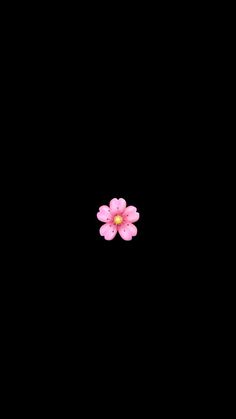 a single pink flower sitting on top of a black surface