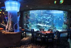 a large aquarium is in the middle of a restaurant with tables and chairs around it