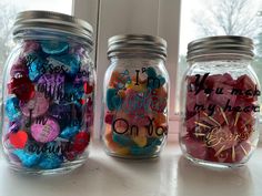 three jars filled with candy sitting on top of a window sill next to each other