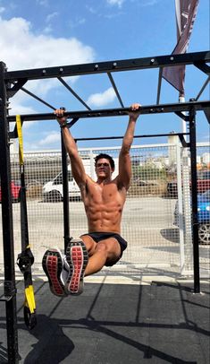 a shirtless man hanging upside down on a pull up bar