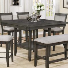 a dining room table with four chairs and a wine glass on the end table in front of it