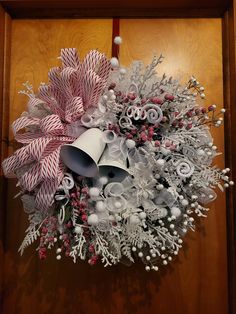 a christmas wreath hanging on a door with bells and candy canes attached to it